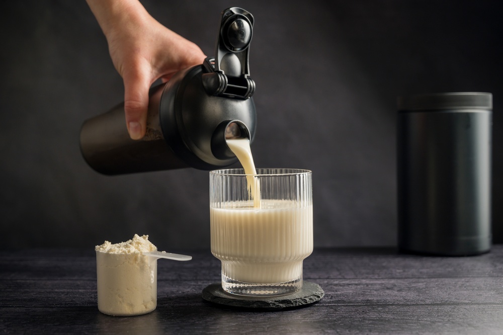 Hand pouring mixed powder supplements into a glass