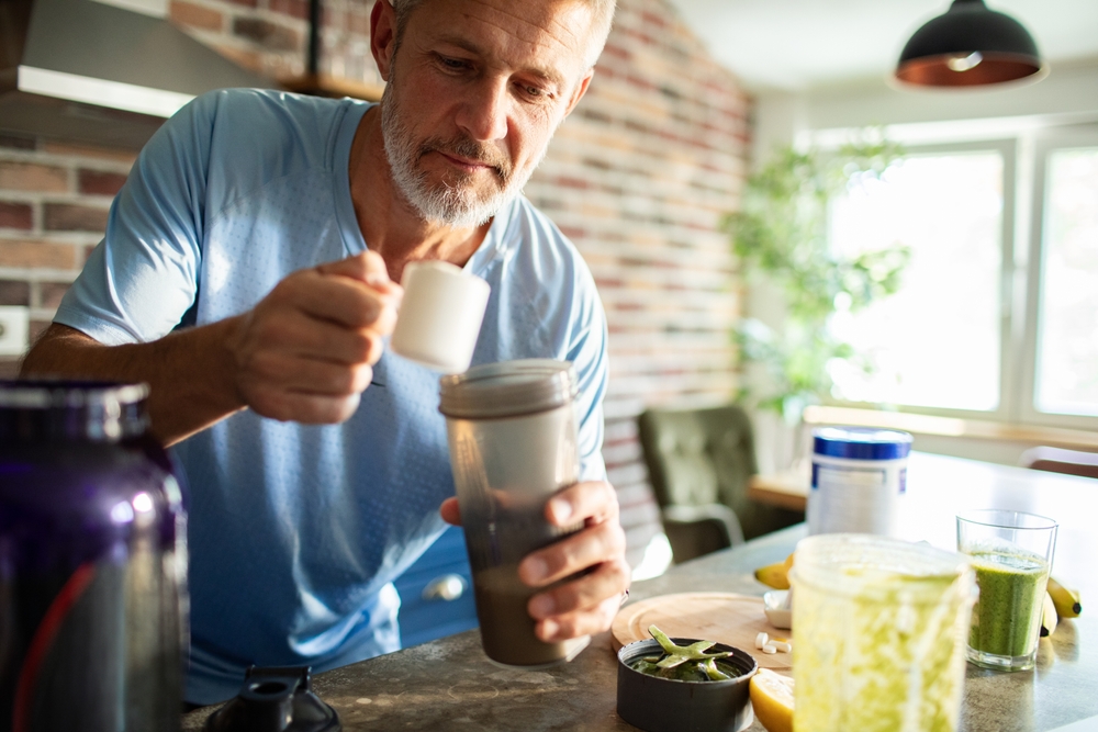 Older man preparing a drink made from powder supplements